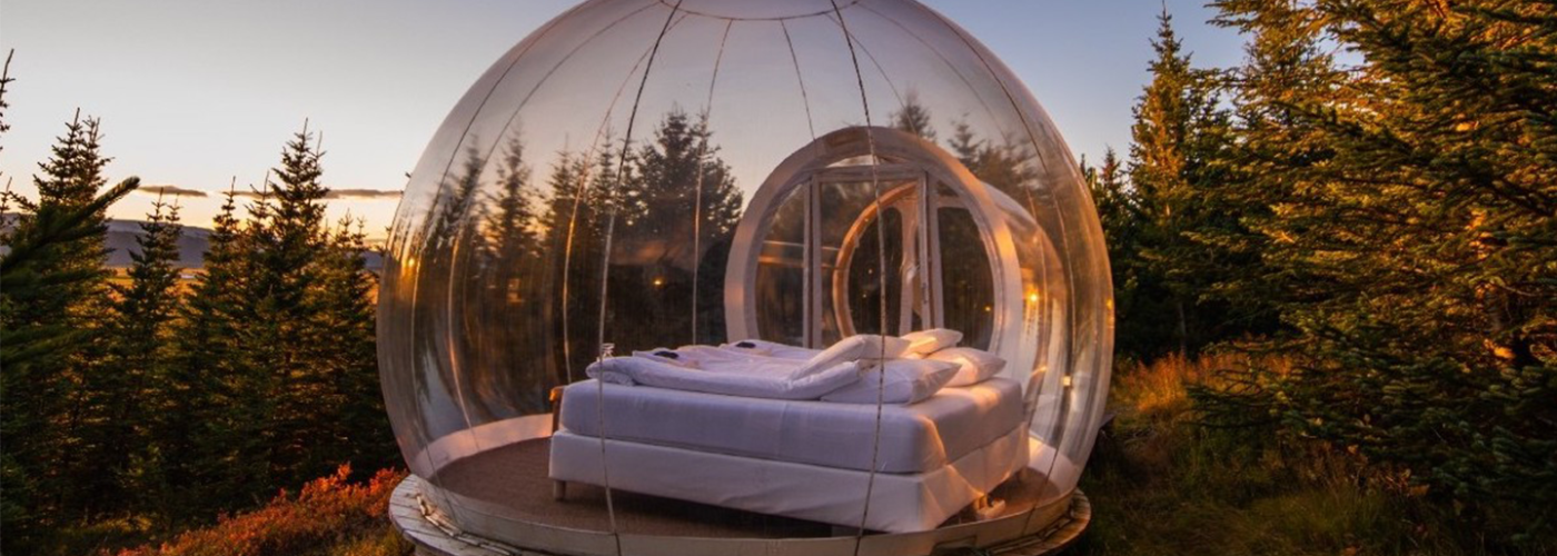 A bed inside an insulated bubble overlooking forest scenery in Iceland