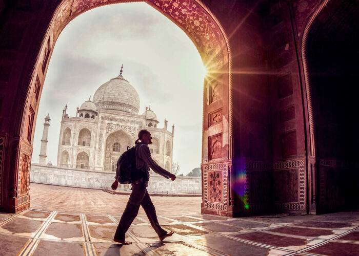 Tourist with backpack walking in the mosque arch near Taj Mahal in Agra