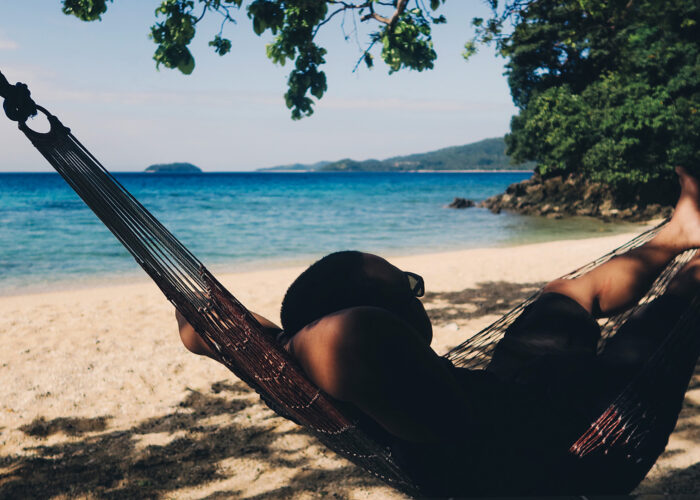 man sits in hammock on a quiet beach