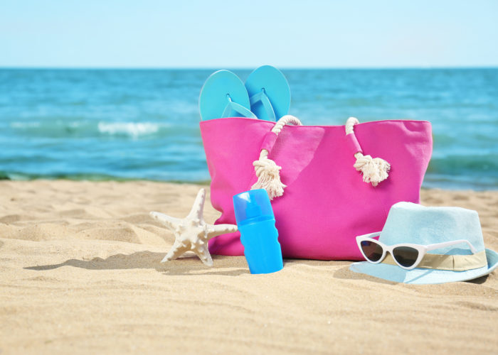 Pink beach bag with blue accessories on the beach