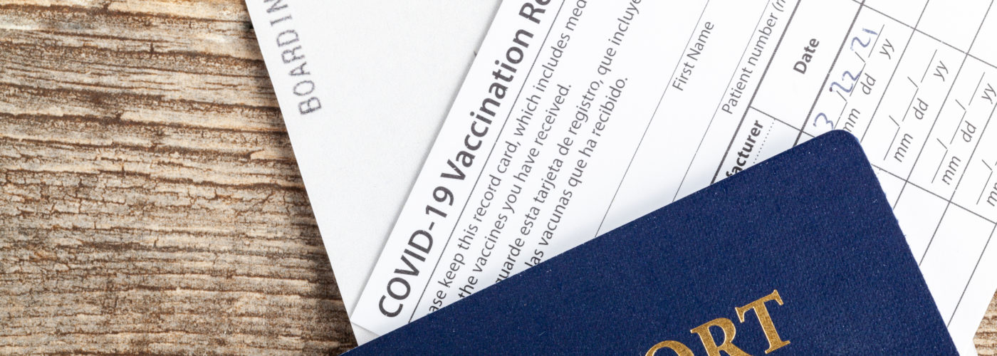 Passport, COVID vaccination card, and boarding pass on a wooden background