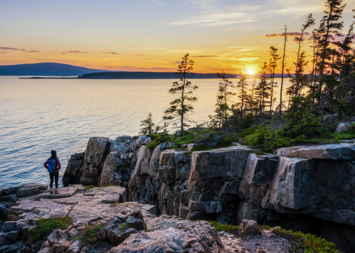 Female Hiker watching a sunset in Acadia National Park, Maine