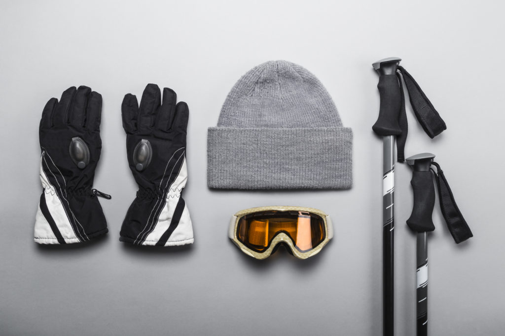 Winter sports gear laid out on a flat grey backdrop